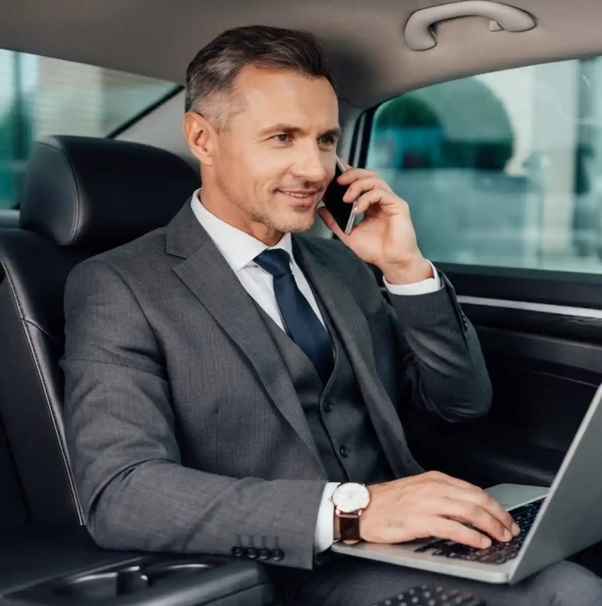 Executive in a suit taking a call from the back seat of a luxury car